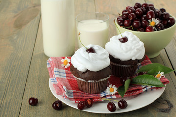 Chocolate cupcakes with cherries on wooden background. top view