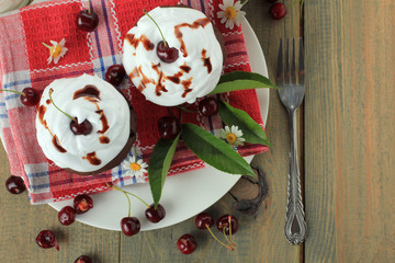 Chocolate cupcakes with cherries on wooden background. top view