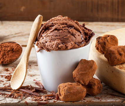 Artisanal home made chocolate ice cream and a spoon on a wooden table with truffles