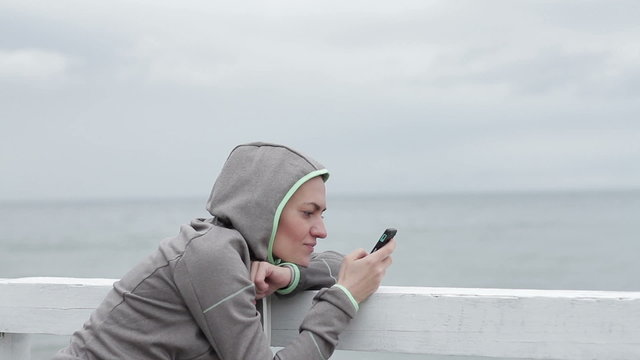 Girl reading or writing sms on her mobile smartphone on sea background