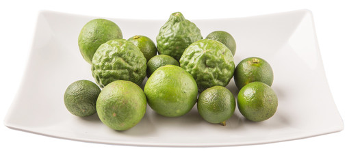 Lime, makrut or kaffir lime and calamansi on white plate