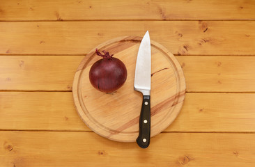 Red onion with a knife on a chopping board