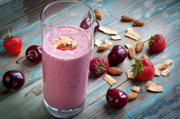 Greek yogurt smoothie milkshake topped with goji berries and coconut shavings.A nutritious breakfast served on a rustic wooden tray