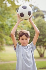 Obraz premium Boy looking at camera and holding a soccer ball in the park