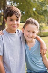 Fototapeta na wymiar Smiling sibling looking at camera in the park