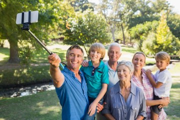 Happy family using a selfie stick in the park