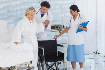 Patient trying to sit on wheelchair with help of doctors 