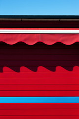The shadow of the awnings on the red wall
