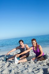 Fototapeta premium Happy couple stretching together beside the water