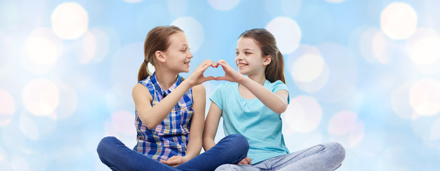 happy little girls showing heart shape hand sign