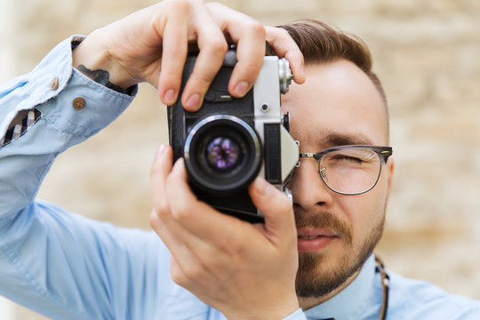 young hipster man with film camera in city