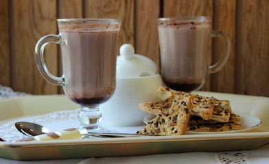 Two mugs with cocoa and cookies.
