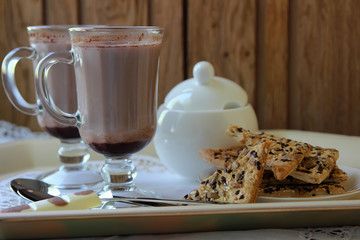 Two mugs with cocoa and cookies.
