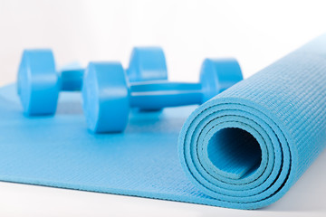 Yoga mat and dumbbells on white background