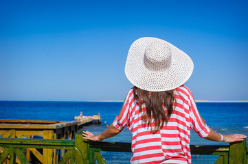 Fototapeta premium Woman in a big white hat looks at sea
