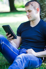 Obraz premium young man sitting on the ground and reading book