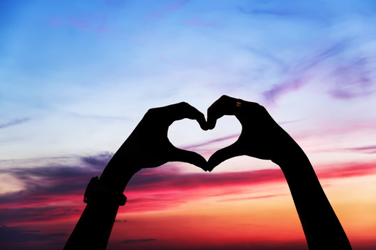 Heart shape of hands against the sky