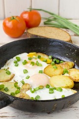 fried potatoes with fried eggs in a frying pan 