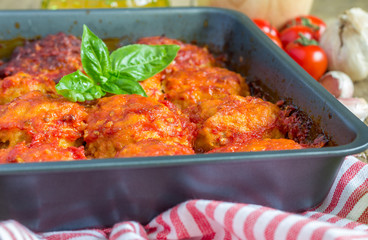 Meatballs with tomato sauce in baking form