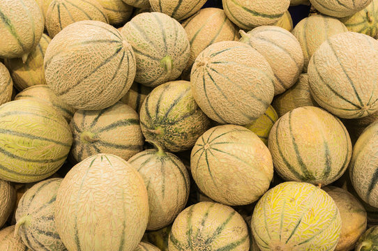 Viele frische Melonen liegen ungeordnet in der Auslage zum Verkauf
