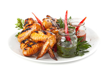 Plate of grilled chicken wings with sauce, isolated on white bac
