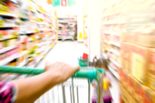 blurred image of woman hand hold shopping cart in supermarket