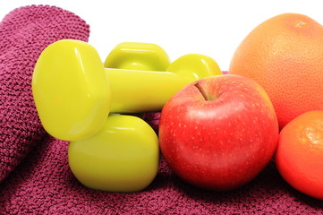 Fresh fruits and green dumbbells on purple towel