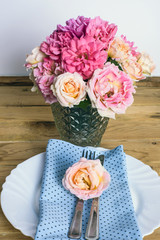 Beautiful festive table setting with roses, candles and napkins 