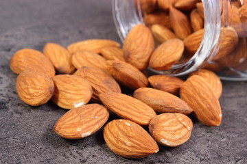 Almonds spilling out of glass jar on concrete structure