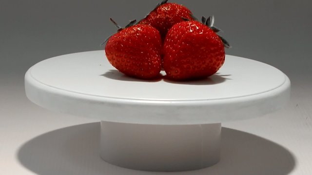 Red strawberry on white plate studio shot