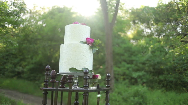 On the antique wooden stand wedding cake in the sunlight