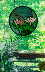 Water lily and frog Stain Glass picture in window looking out at deck and woods