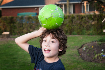 young boy playing with a green soccer ball in the backyard