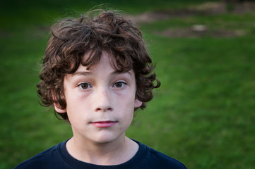 young brown haired boy outdoors on a green grassy yard