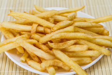 Potatoes fries in a little white paper bag on wood board