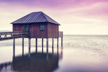 The wooden building on stilts over Lake Constance at dusk-vertical.