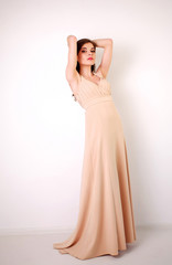 Fototapeta na wymiar Fashion young brunette woman in pastel long dress in studio 
