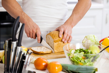 Close-up of a chef holding a baguette in front of a bamboo cutti