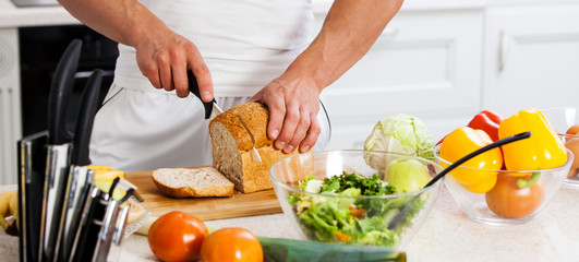 Close-up of a chef holding a baguette in front of a bamboo cutti