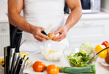Obraz na płótnie Canvas Handsome man cooking at home preparing salad in kitchen.
