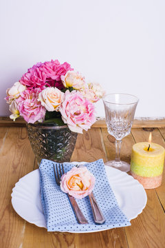 Beautiful festive table setting with roses, candles and napkins 