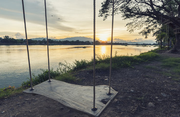 lone swing at river side and sunset ,Thailand . Vintage Tone.