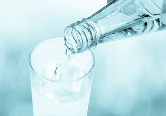 Drinking water is poured from a bottle into a glass