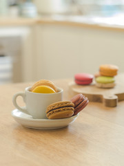 French macaron cookie in cup and wooden tray on wooden table in