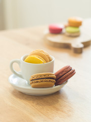 French macaron cookie in cup and wooden tray on wooden table in