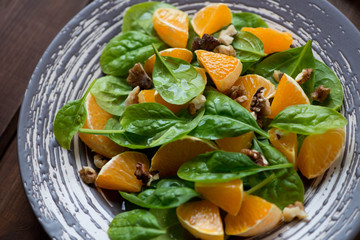 Salad with sliced mandarins, spinach leaves and walnuts