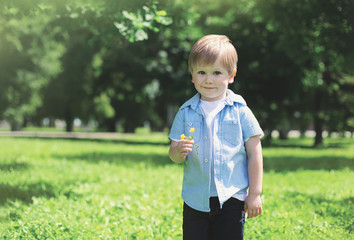 Portrait of cute little boy child with flower outdoors on the na