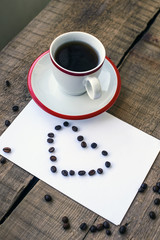 coffee cup and coffee beans in heart shape on wooden background
