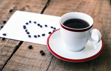 coffee cup and coffee beans in heart shape on wooden background
