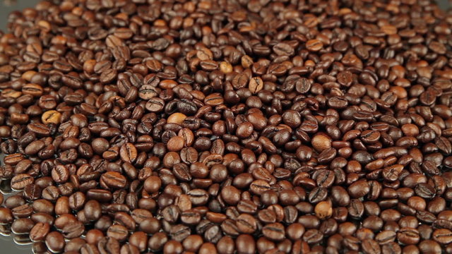 Roasted coffee beans rotates on the table.